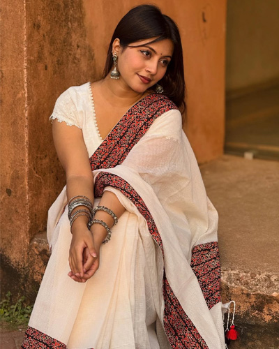 Beautiful Khushi Indian Escorts in Indore leaning forward softly, dressed in traditional Indian wear with silver jewelry