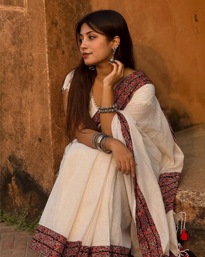 Khushi Indian Escorts in Indore captured in a serene close-up, wearing a white saree, silver earrings, and bangles while posing elegantly in natural light