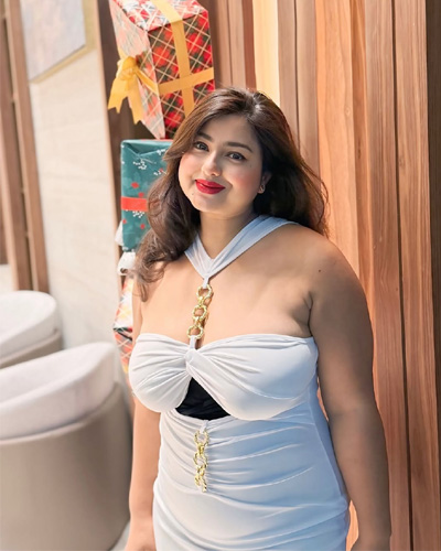 Prisha VIP Escorts in Indore posing in a white stylish dress beside gift decorations
