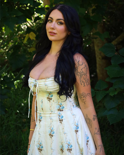 Natural portrait of Zoya Foreigner Escorts in Indore posing on a flower-covered ground with visible arm tattoos